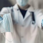 Doctor hold the antiseptic and masks in his hand