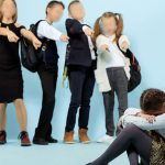 Little girl sitting alone on floor and suffering an act of bullying.