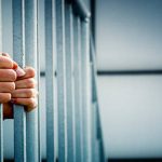 A prisoner behind the jail cell bars .